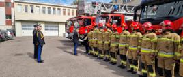Komendant główny Państwowej Straży Pożarnej wita się ze strażakami ustawionymi w rzędzie za nim stoi kierownictwo Komendy Wojewódzkiej Państwowej Straży Pożarnej w Gdańsku.