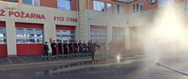 Na zdjęciu widzimy strażaka przechodzącego na emeryturę podczas pokonywania szpaleru utworzonego z kurtyn wodnych.