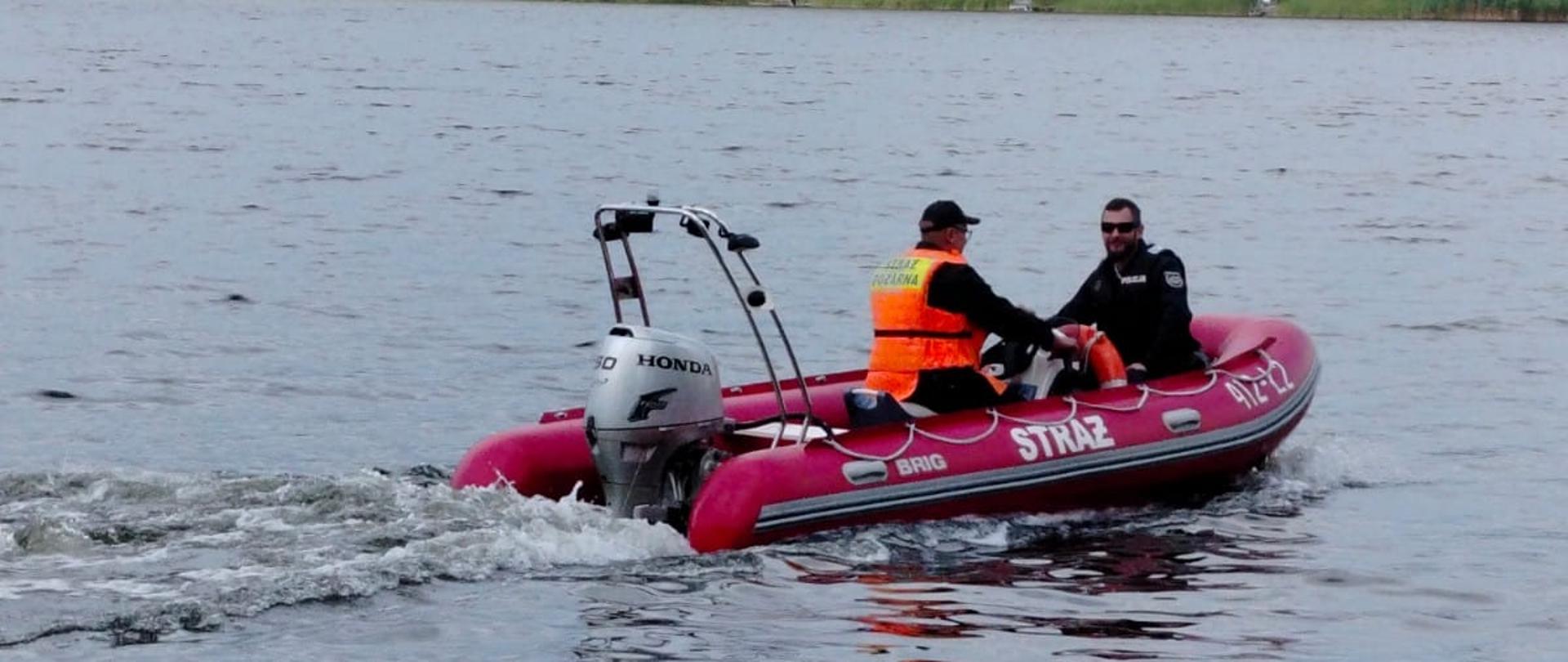 Strażak wraz z policjantem patrolują na łódce jezioro