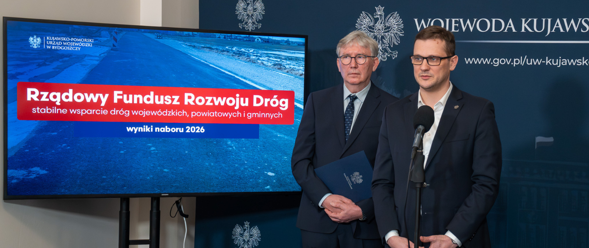 Konferencja prasowa Wojewody Kujawsko-Pomorskiego Michała Sztybla w temacie Rządowego Funduszu Rozwoju Dróg z udziałem Starosty Powiatu Nakielskiego Krzysztofa Błońskiego oraz Dyrektor Wydziału Infrastruktury w KPUW Katarzyny Szpakowskiej w Kujawsko-Pomorskim Urzędzie Wojewódzkim. W tle znajduje się prezentacja ze szczegółami omawianymi podczas konferencji.