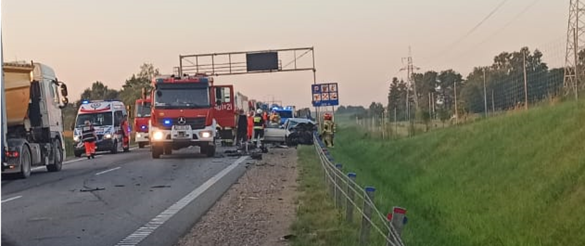 Na zdjęciu widoczny jest wrak samochodu, Zespół Ratownictwa Medycznego i pojazd ratowniczo - gaśniczy.