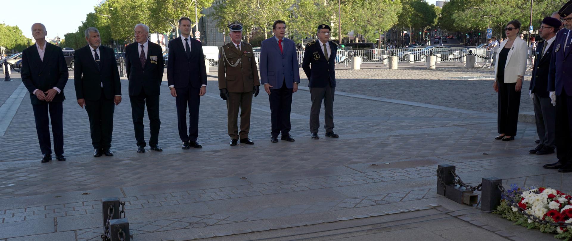 Des hommes se tiennent en rang devant la tombe du Soldat inconnu, sous l'Arc de Triomphe.
