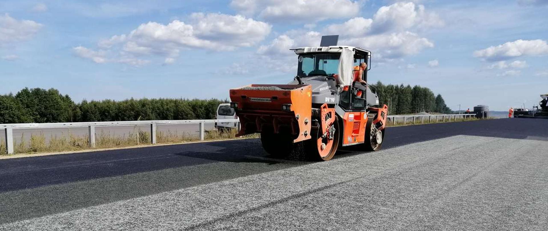 Zdjęcie przedstawia budowę drogi ekspresowej S6 - wykonywanie nawierzchni bitumicznej. Na pierwszym planie widać walec drogowy.