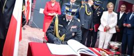 Na zdjęciu komendant główny PSP podczas wpisu do księgi pamiątkowej