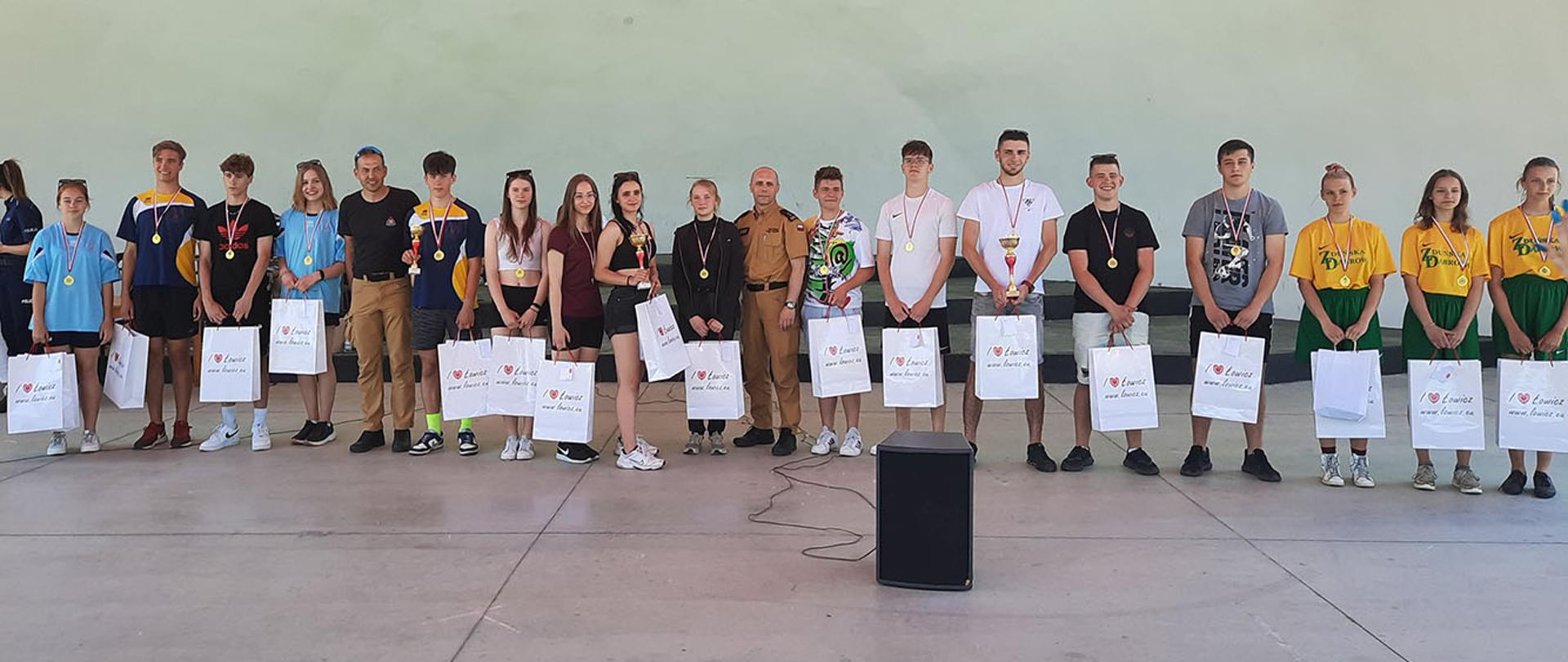 zdjęcie pamiątkowe nagrodzonych zawodników pozujących z mistrzem olimpijskim Zbigniewem Bródką i komendantem powiatowym Arkadiuszem Makowskim