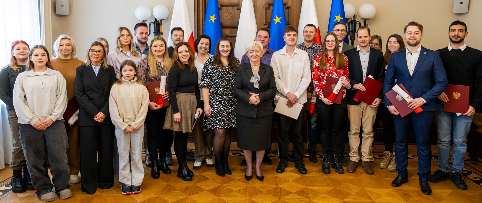 Pamiątkowa fotografia wojewody łódzkiego Doroty Ryl z nowymi obywatelami Polski 