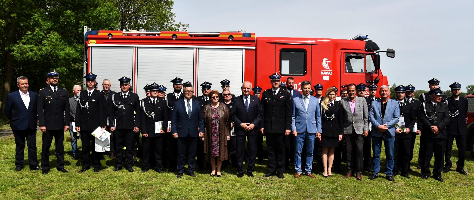 Wspólne zdjęcie uczestników uroczystości na tle wozu OSP Krasowiec