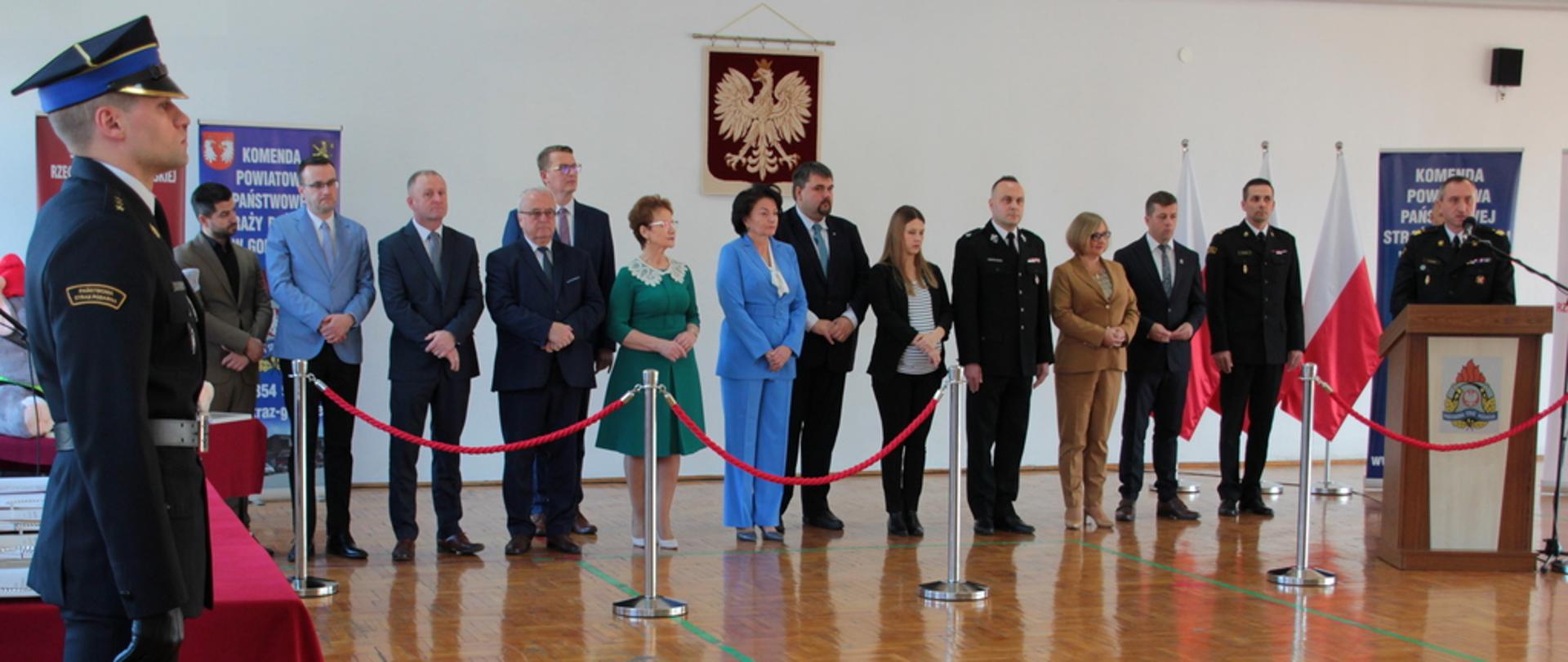 Zajęcie przedstawia zaproszonych gości: Małopolskiego Komendanta Wojewódzkiego, Komendanta Powiatowego Państwowej Straży Pożarnej w Gorlicach, samorządowców terytorialnych podczas uroczystości wręczenia promes finansowych dla Młodzieżowych Drużyn Pożarniczych z terenu powiatu gorlickiego.