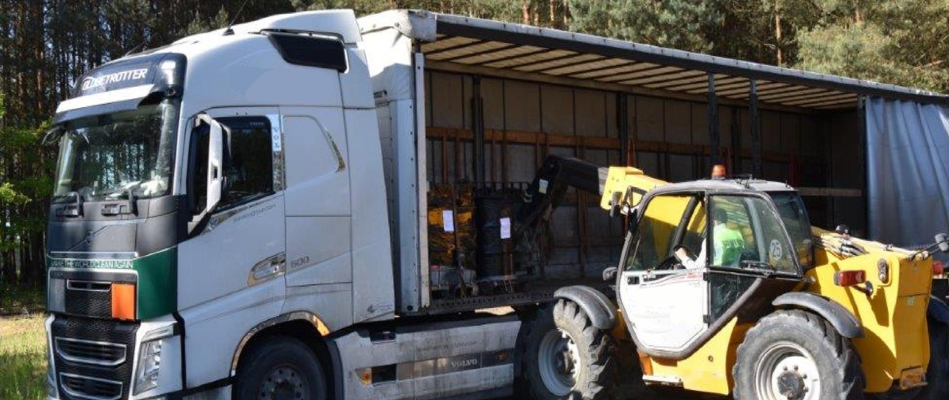 Podnośnik widłowy ładuje sześcienne pojemniki o pojemności 1000 litrów na naczepę samochodu ciężarowego.