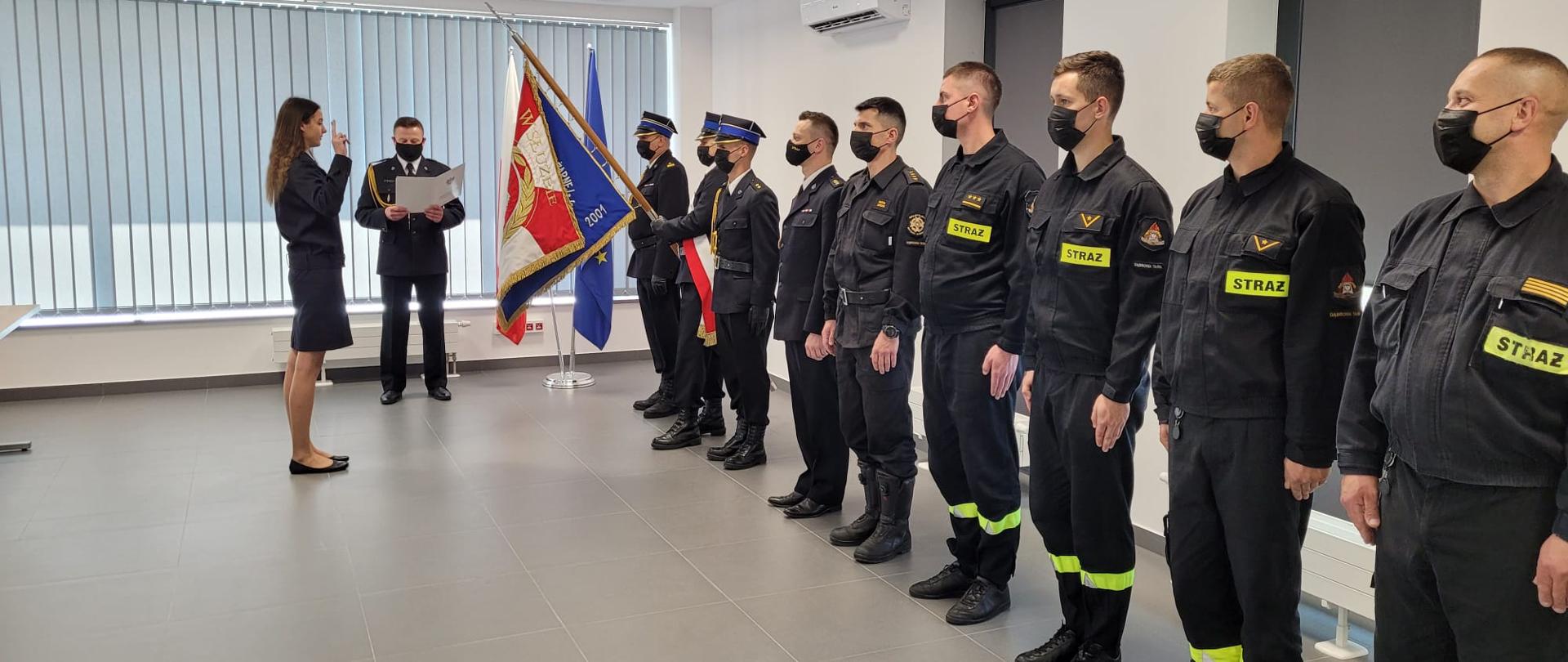 Na zdjęciu strażacy na sali wykładowej podczas ślubowania, w obecności sztandaru 