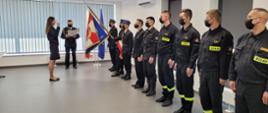 Na zdjęciu strażacy na sali wykładowej podczas ślubowania, w obecności sztandaru 