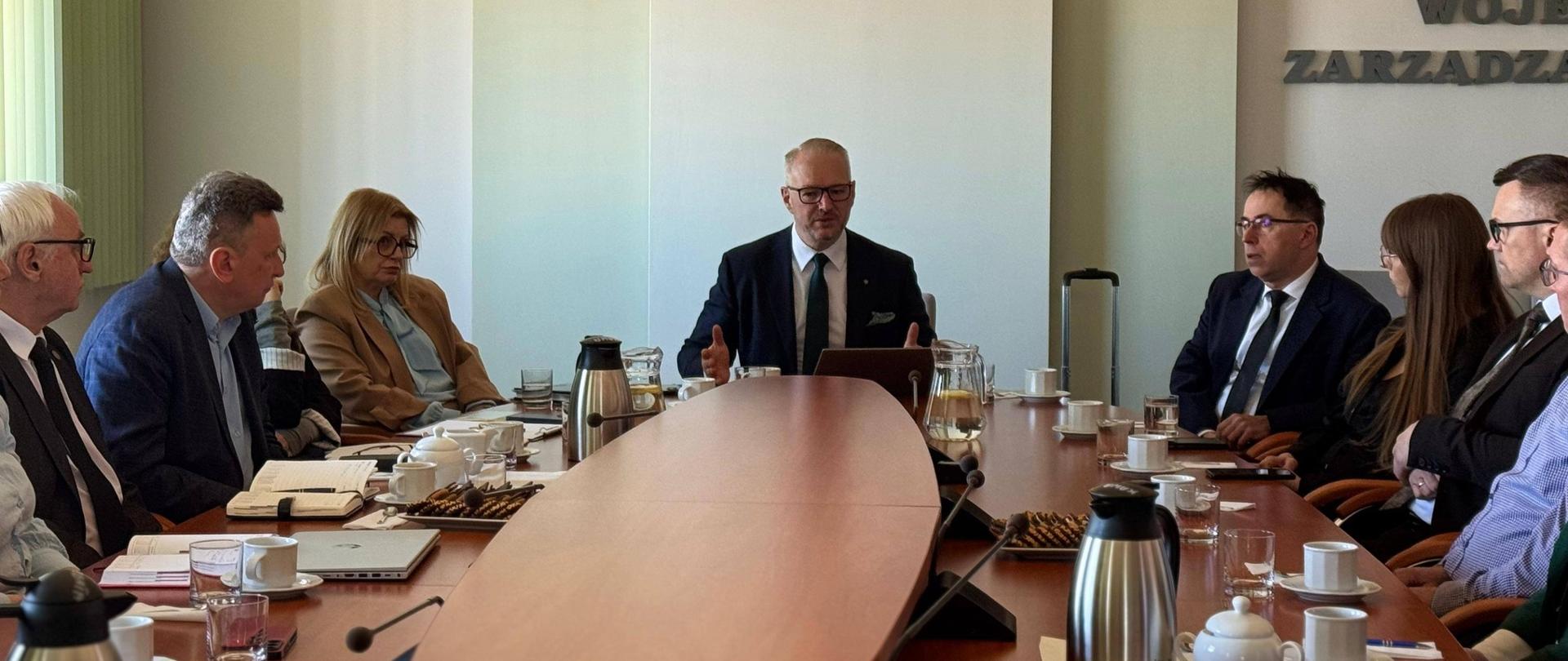 grono oficjeli siedzi przy stole, rozmawiają