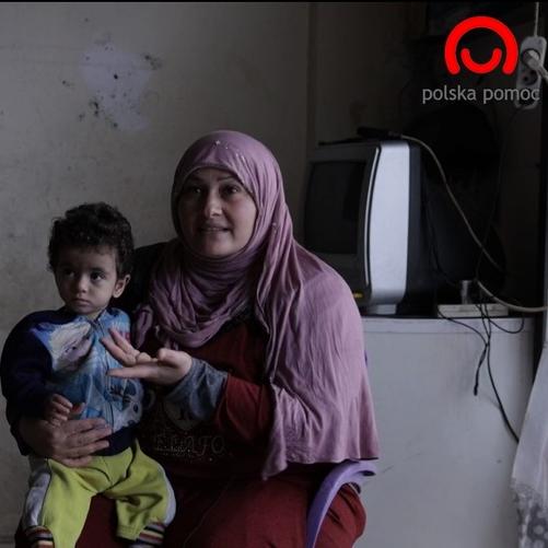 Kobieta z dzieckiem na kolanach i mężczyzna siedzą na krzesłach