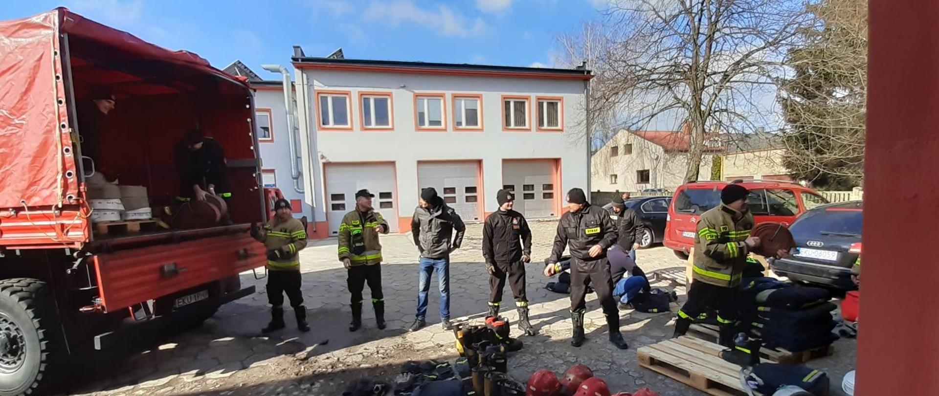 Strażacy Komendy Powiatowej PSP w Kutnie układają w pojeździe zebrany sprzęt pożarniczy oraz odzież specjalną w postaci butów, hełmów