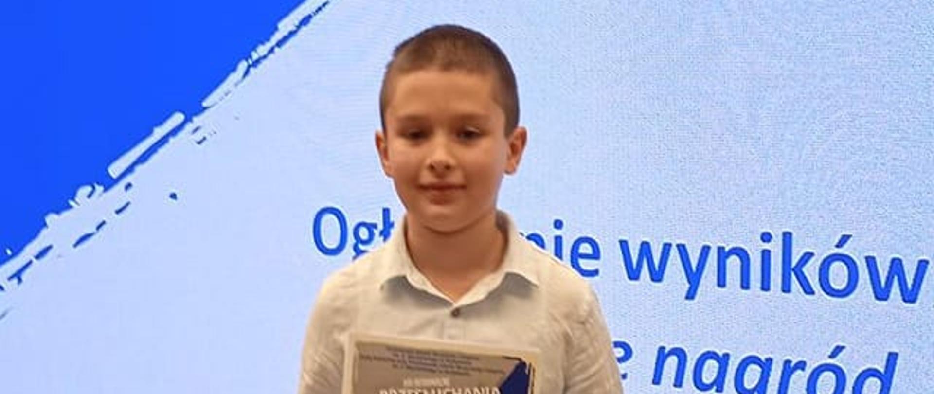 Uczeń klasy gitary trzymający dyplom za zajęcie II miejsca w XIII Przesłuchaniach Uczniów Klas Gitary I Zespołów Gitarowych - Strzyżów 18 Maja 2023 r.