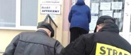 Na zdjęciu strażak OSP w ubraniu koszarowym pomaga starszej osobie wejść po schodach do przychodni NFZ.