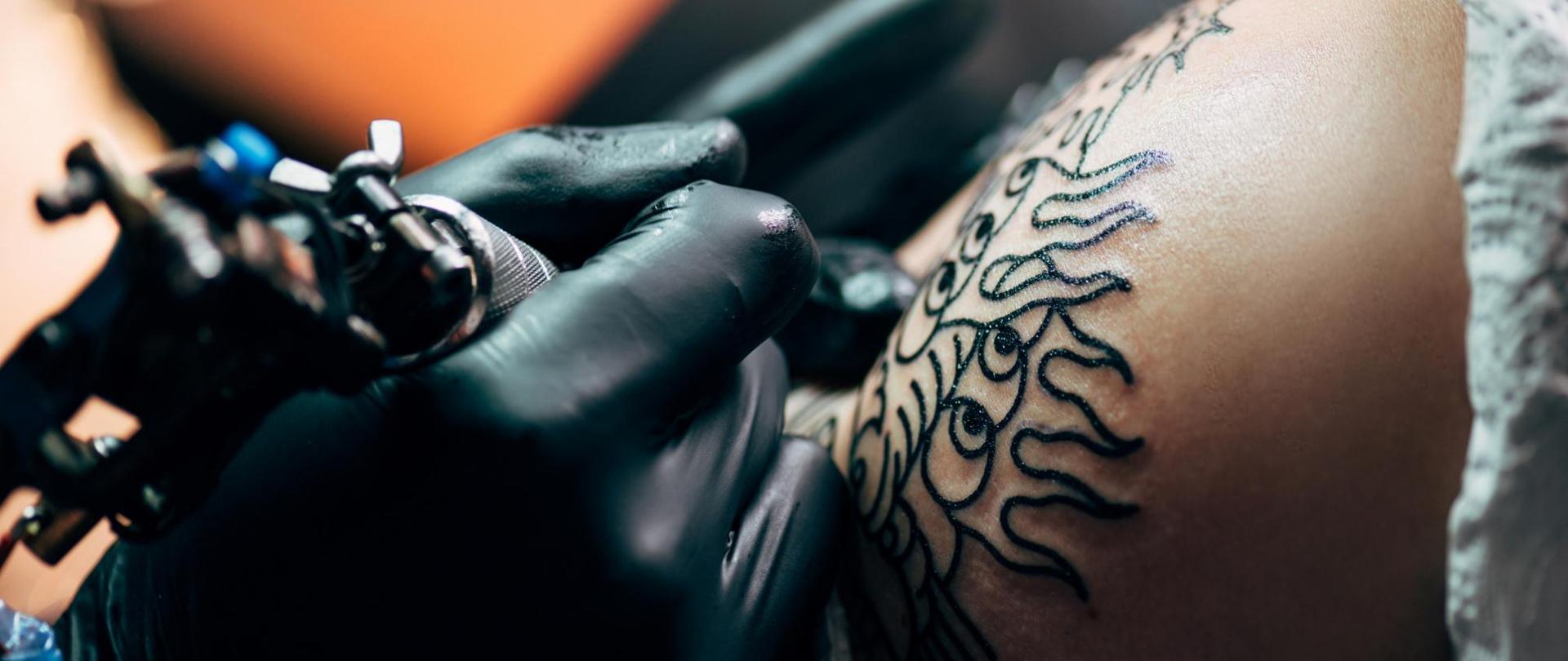 Na zdjęciu widoczne jest wykonywanie tatuażu.