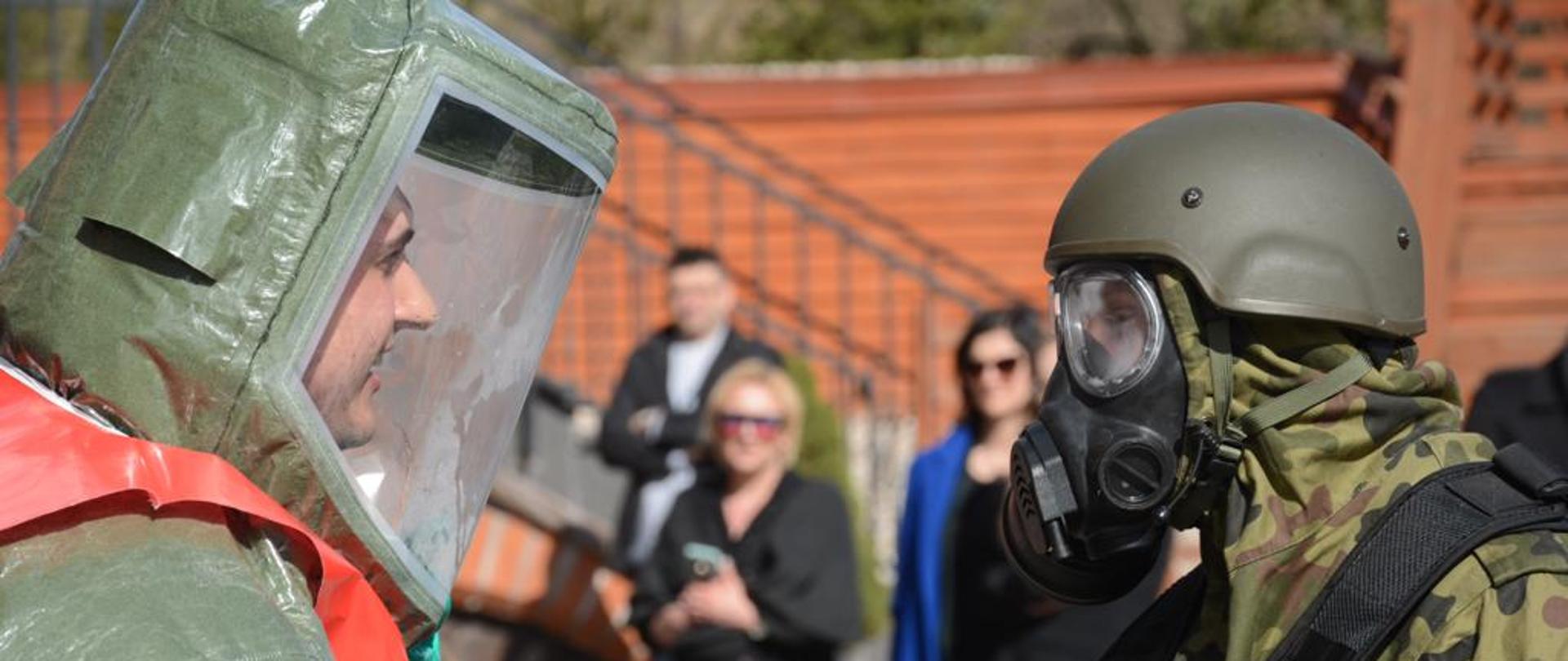 Na zdjęciu po lewej ratownik w specjalnym uniformie, po prawej ratownik w mundurze wojskowym oraz w masce przeciwchemicznej