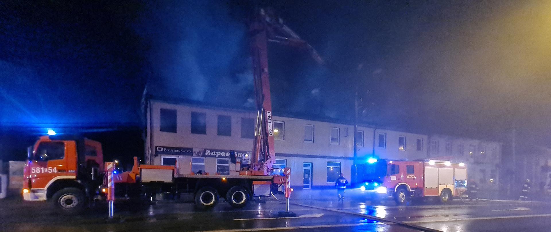 Na zdjęciu widać płonący dach budynku oraz samochody ratowniczo gaśnicze w tym podnośnik.