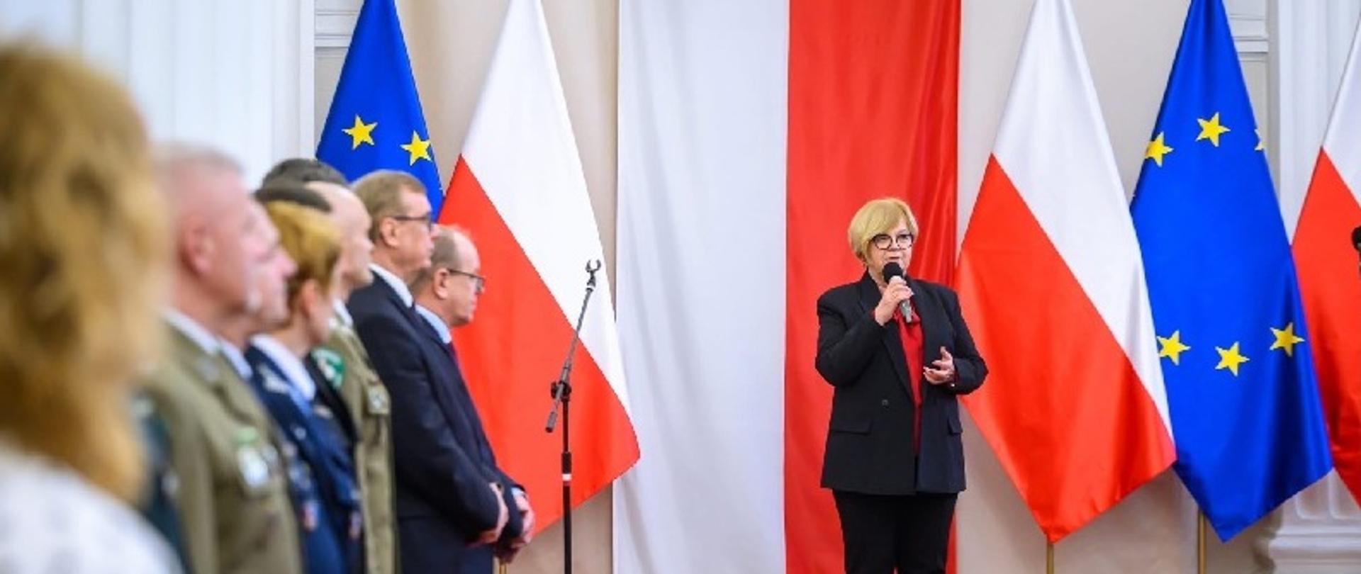 Uczestnicy spotkania stoją w sali. Przemawia do nich Wojewoda Podkarpacki. Zdjęcia Jerzy Żygadło/ PUW Rzeszów