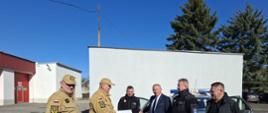 Zdjęcie przedstawia moment przekazania samochodu operacyjnego z Komendy Powiatowej PSP w Lubinie do OSP Chobienia. Przekazanie odbywa się na placu wewnętrznym Komendy Powiatowej PSP w Lubinie.