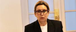 Kobieta przy stole konferencyjnym, przed nią tabliczka Iwona Kozłowska