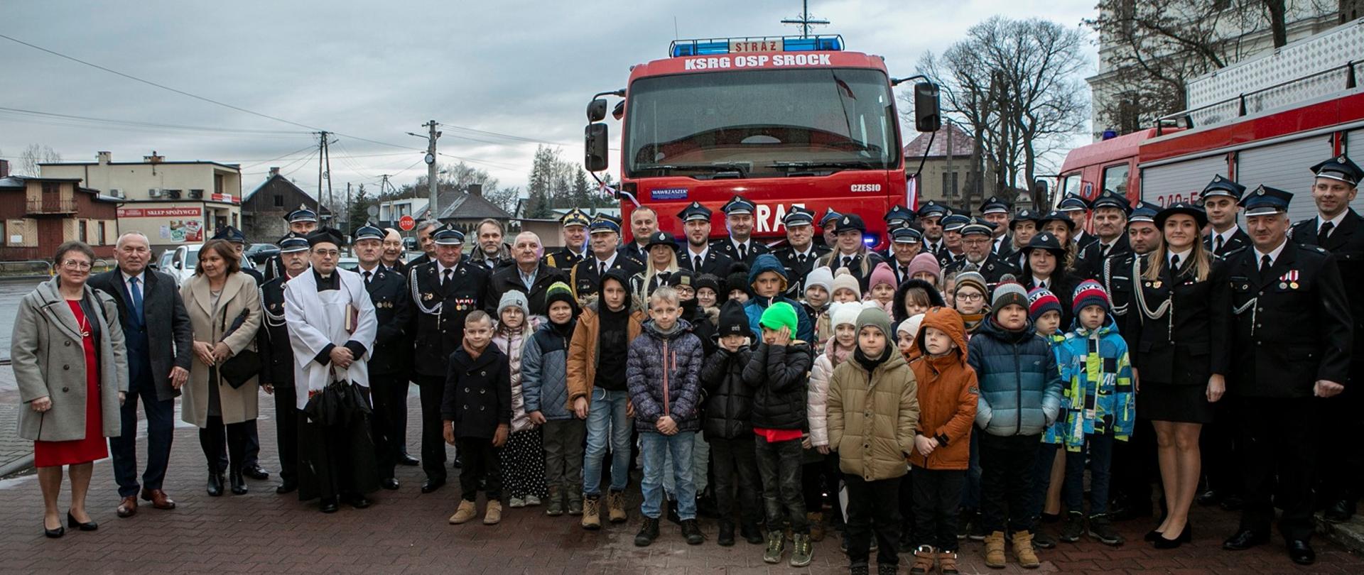 strażacy PSP i OSP oraz pozostali uczestniczy uroczystości pozują do zdjęcia na tle samochodu gaśniczego