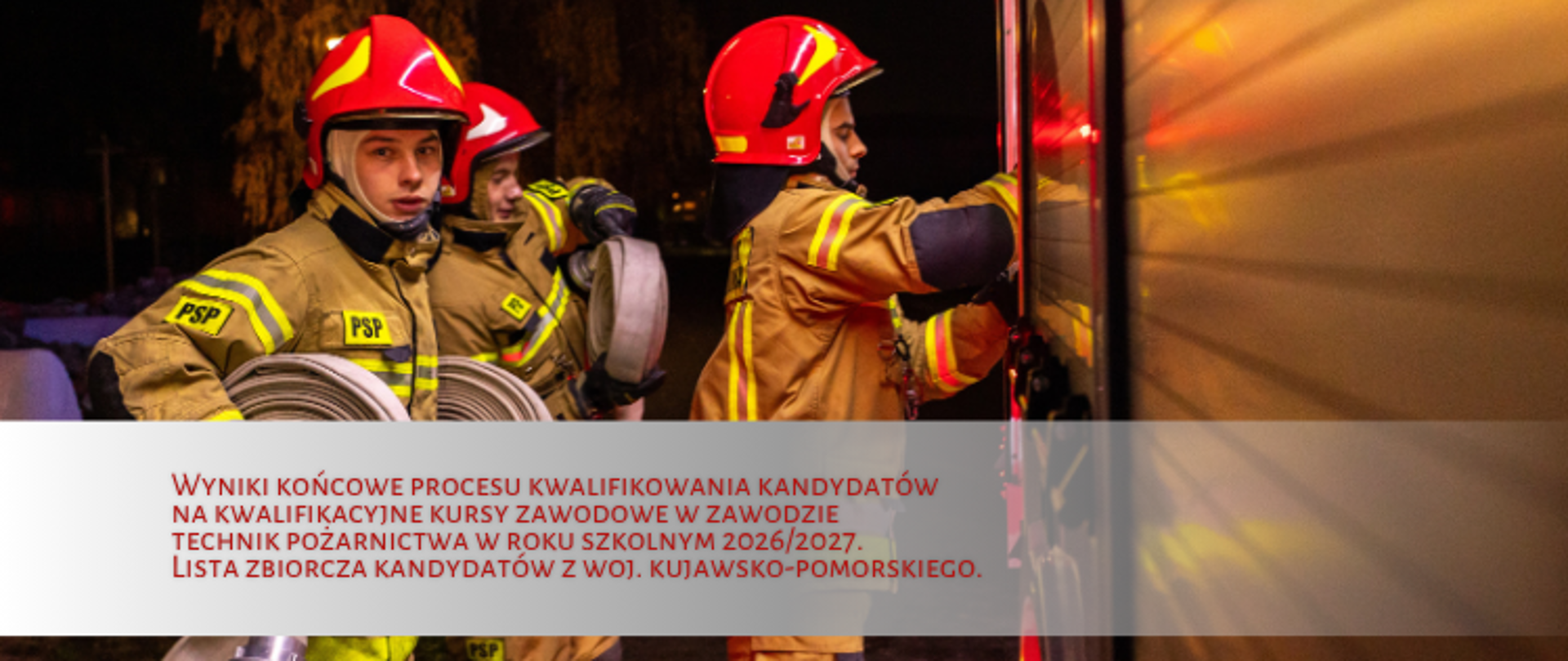 Trzech strażaków w ubraniu specjalnym przy skrytkach pojazdu gaśniczego. Dwóch z nich trzyma w rekach węże zwinięte w krąg. Z przodu pasek z napisem informacyjnym.
