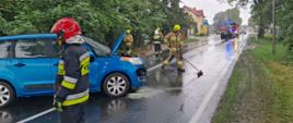 Na zdjęciu widać strażaków, uszkodzone auto osobowe oraz w tle wóz strażacki 