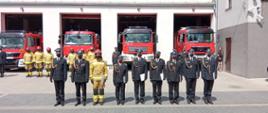 Widać strażaków, którzy otrzymali awans na wyższy stopień oraz cztery samochody straży pożarnej