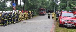 Strażacy ustawieni w dwuszeregu w miejscu koncentracji sił i środków podczas omawiania głównych założeń ćwiczeń "WYSPA W OGNIU" odbywających się na Wyspie Edwarda w Zaniemyślu.