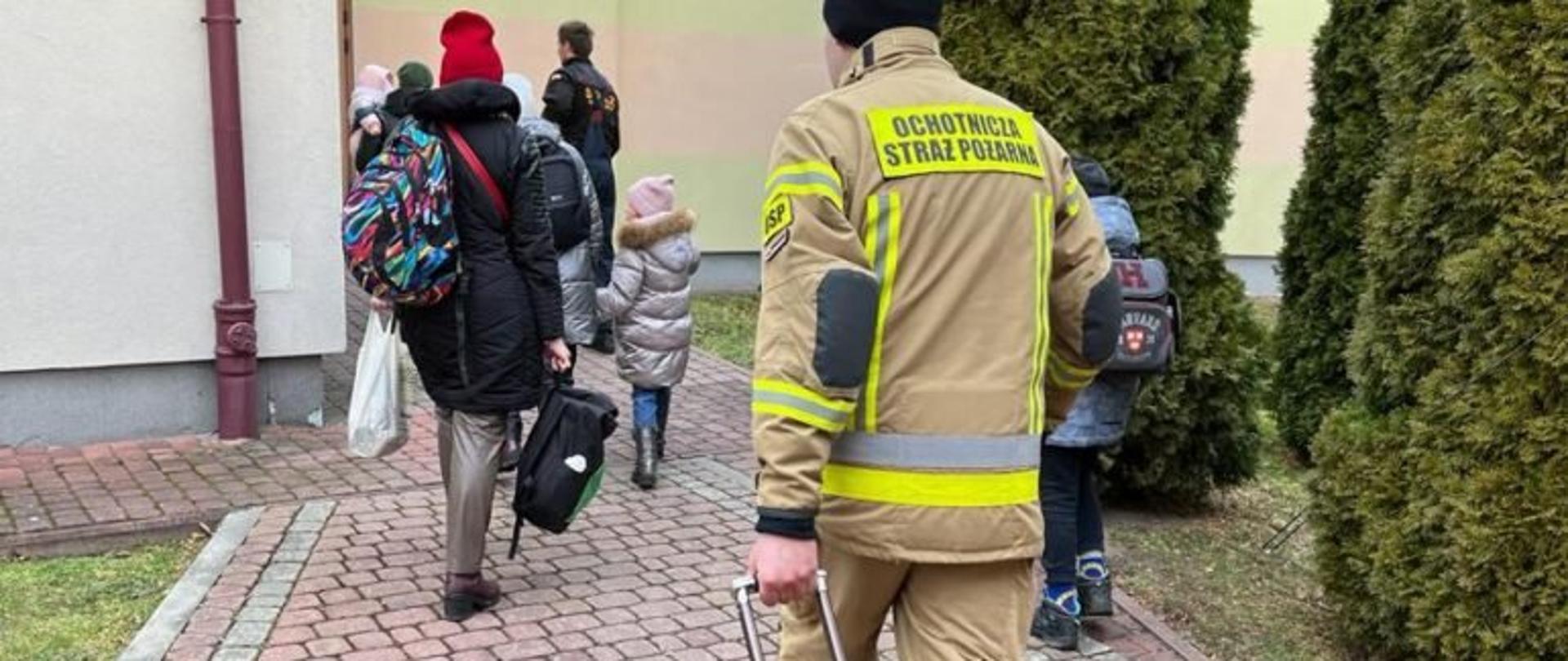 Strażak idący za grupą uchodźców