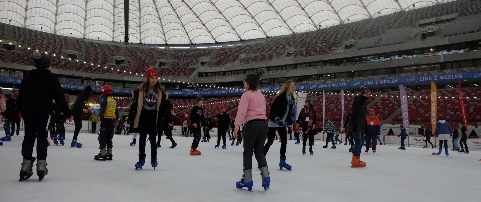 Dzieci jeżdżące na łyżwach na stadionie PGE Narodowy w Warszawie. 
