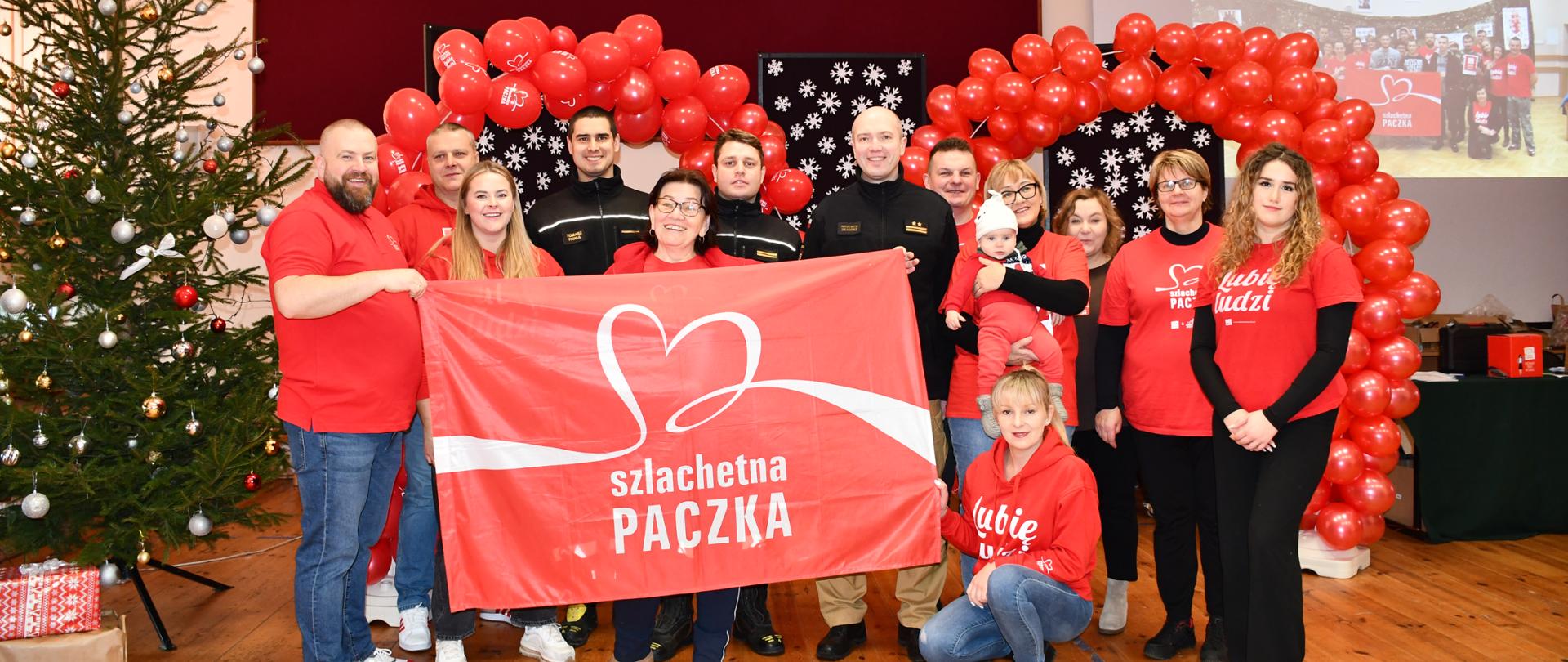 Na zdjęciu widzimy strażaków wraz z wolontariuszami Szlachetnej Paczki pozujących do zdjęcia.