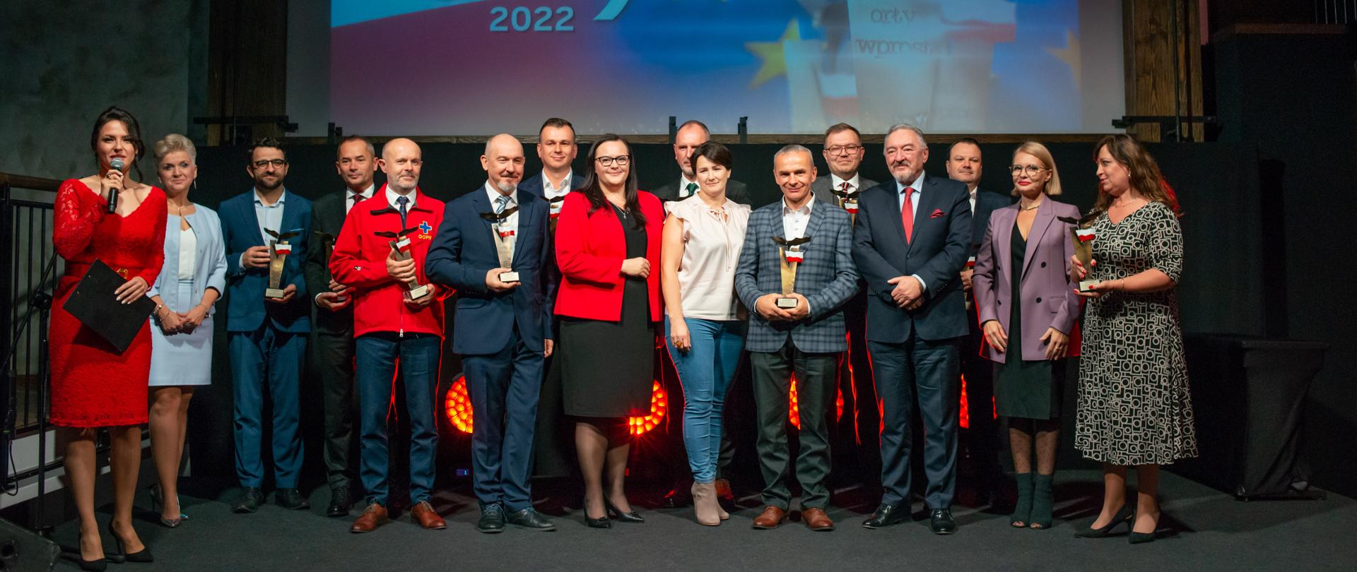 Grupa osób ze statuetkami w rękach pozuje w grupie do zdjęcia