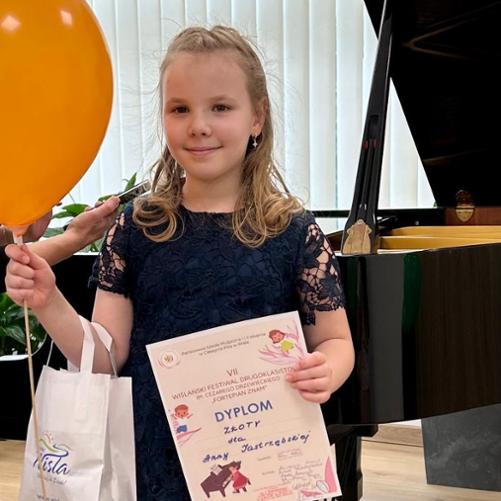 Dziewczynka trzyma dyplom i balonik.