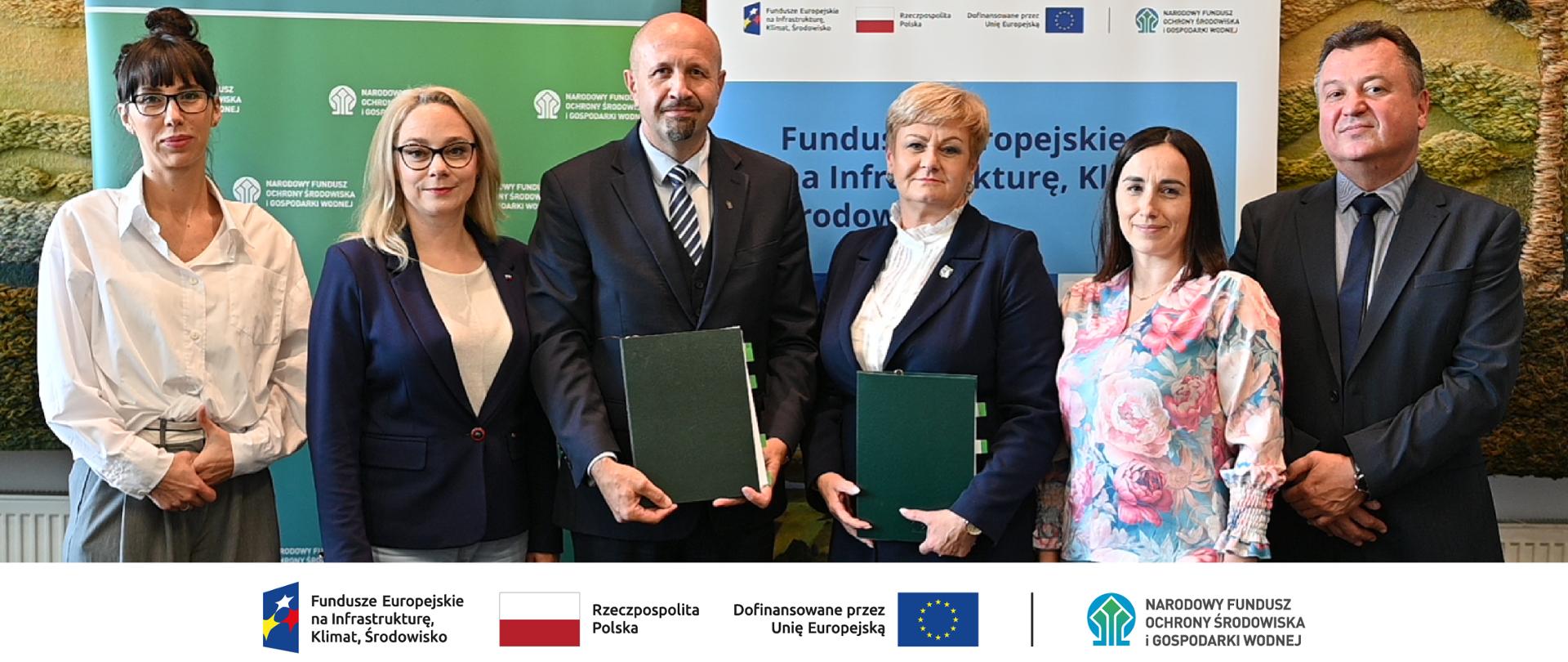 Na zdjęciu od lewej: Karolina Falkiewicz doradca Departament Adaptacji do Zmian Klimatu, Żaneta Cwalina-Śliwowska posłanka, Robert Gajda zastępca prezesa zarządu NFOŚiGW, Piotr Wojciech Płochocki burmistrz Wyszkowa, Anna Osowiecka – skarbnik gminy Wyszków, Robert Markiewicz zastepca dyrektora Departamentu Adaptacji do Zmian Klimatu. Na dole ciąg znaków, logotypy od lewej: FEnIKŚ, flaga Rzeczypospolita Polska, flaga UE Dofinansowane przez UE, NFOŚiGW.