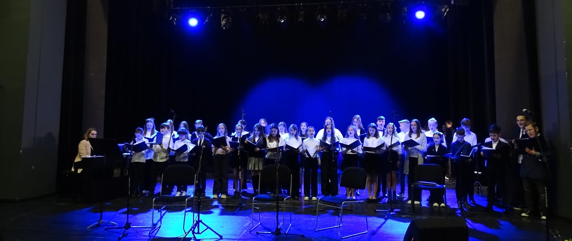 Scena sali teatralno widowiskowej MCK PGE Giganty Mocy w Bełchatowie, na scenie chór Państwowej Szkoły Muzycznej I stopnia w Bełchatowie w czasie Koncertu Wiosennego który odbył się 30 marca 2923 roku