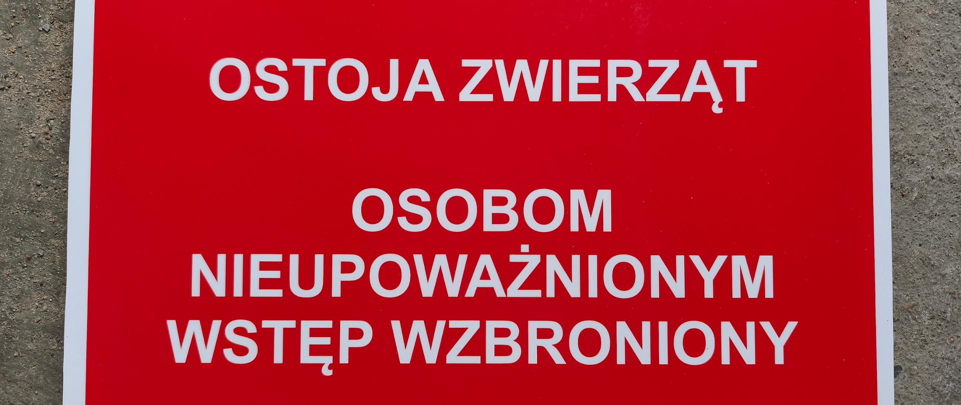 Na zdjęciu tablica na czerwonym tle z białym napisem ostoja zwierząt osobom nieupoważnionym wstęp wzbroniony