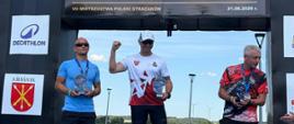 trzy osoby stojące na podium ze statuetkami