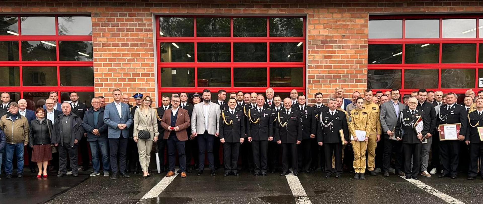 Na zdjęciu znajdują się osoby ustawione do zdjęcia przed garażem