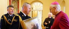 strażak przekazuje obraz pamiątkowy arcybiskupowi Gądeckiemu