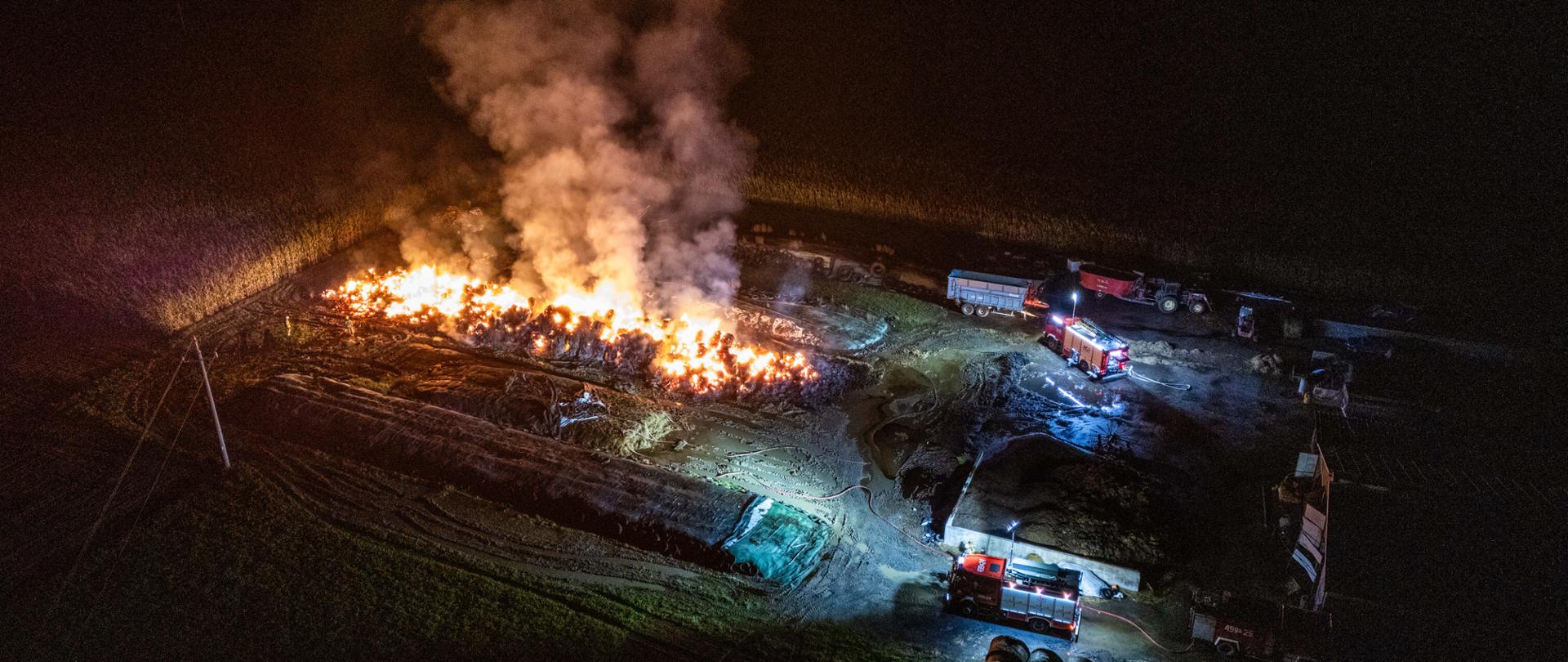 zdjęcie przedstawia strażaków wraz z pojazdami pożarniczymi podczas działań gaśniczych stogu
