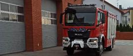 nowy samochód strażacki na tle budynku Komendy