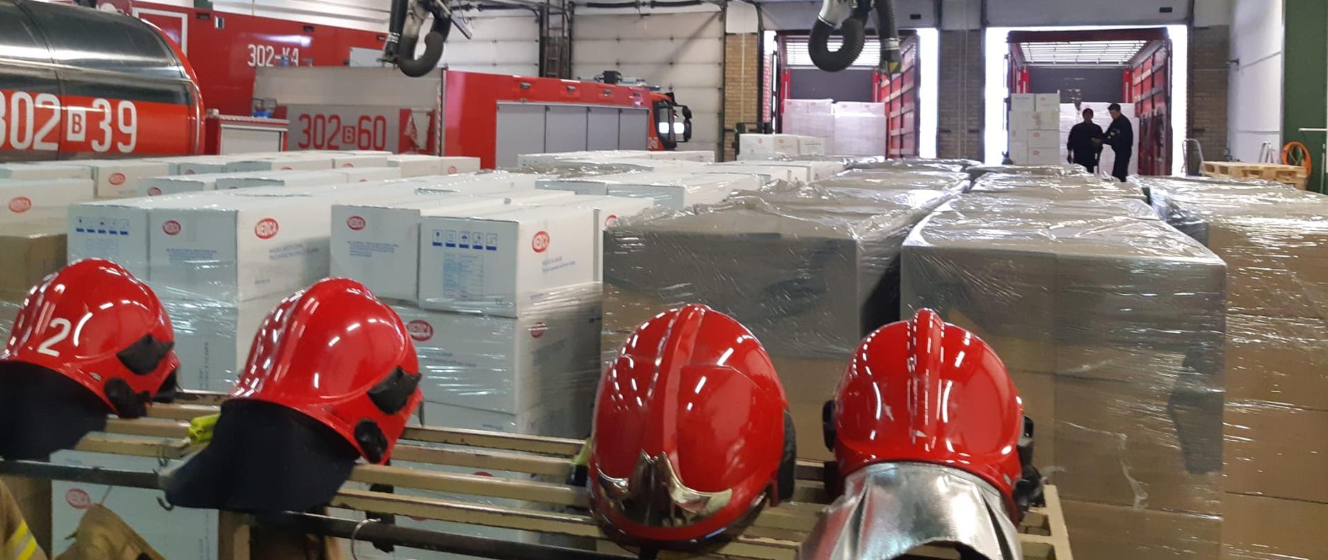 Przedstawia zgromadzone w garażu strażnicy JRG 2 maseczki w kartonach na paletach.