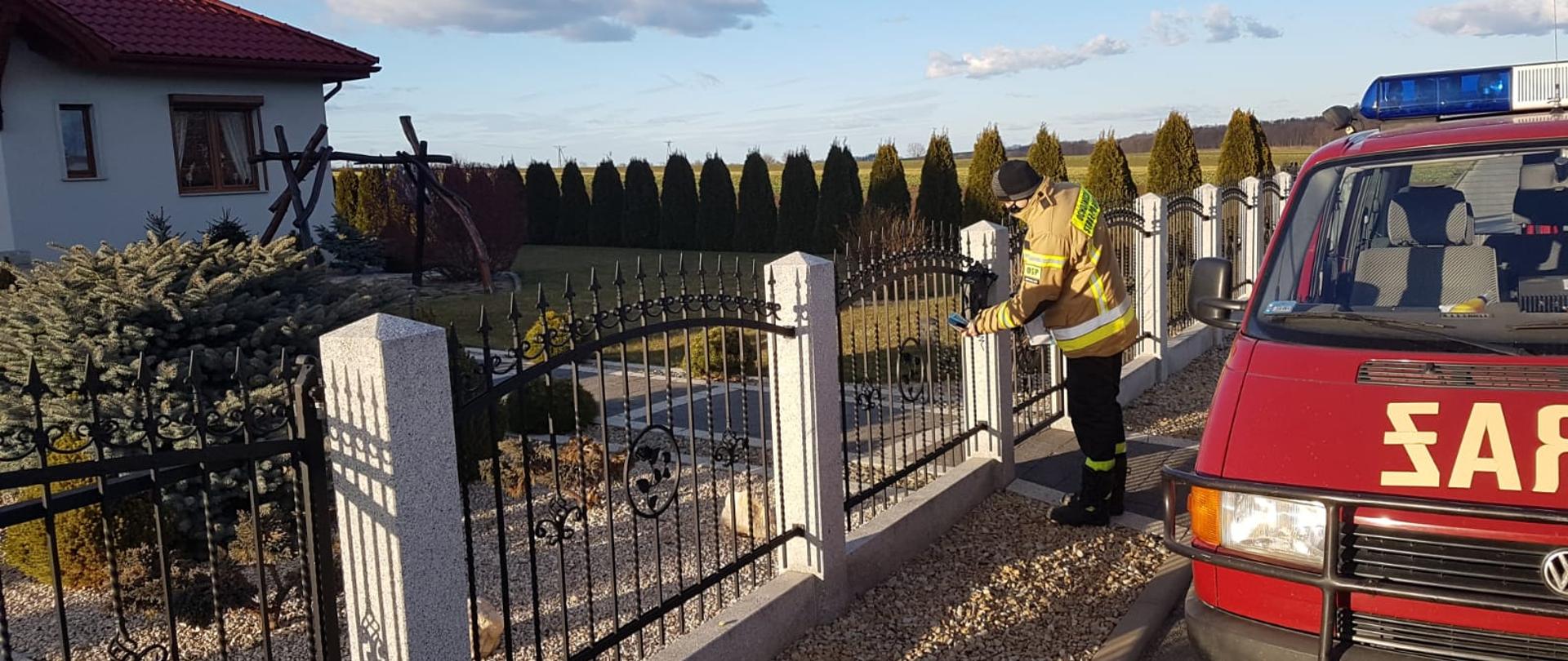 Obraz przedstawia strażaka w trakcie dystrybucji ulotek informacyjnych