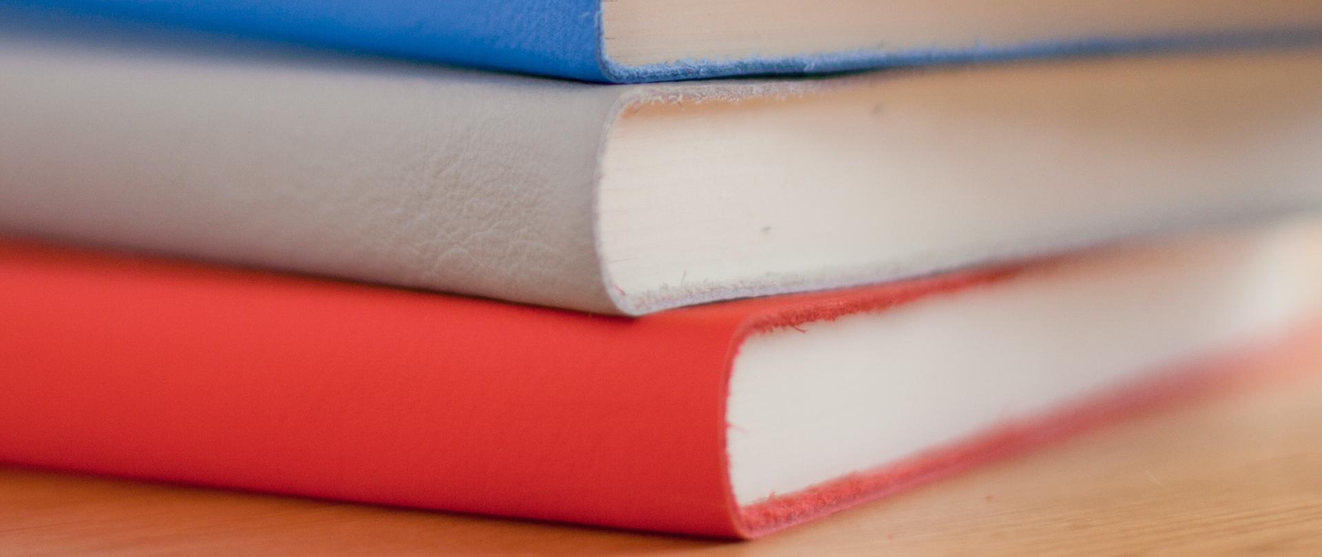 Stos kolorowych książek leży na blacie.