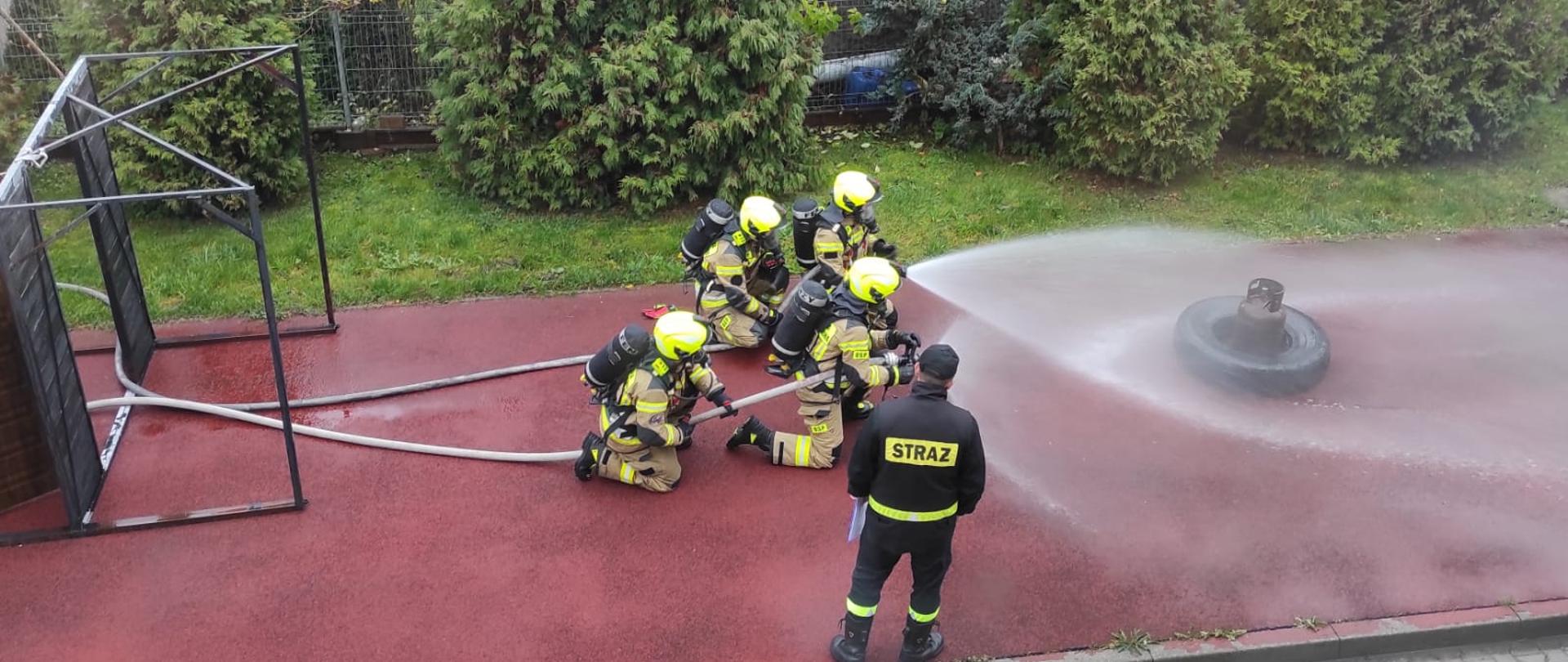Zdjęcie przedstawia druhów w trakcie zaliczenia działań gaśniczych