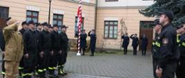 Funkcjonariusze Państwowej Straży Pożarnej wraz z Zastępcą Komendanta Miejskiego st.bryg. Piotrem Gąską przed budynkiem Centrum Edukacji i Historii Warszawskiej Straży Pożarnej podczas uroczystej zmiany służby z okazji Narodowego Święta Niepodległości.