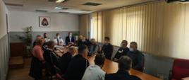 Strażacy na sali konferencyjnej siedzący przy stole podczas spotkania dotyczącego projektu ustawy o OSP.